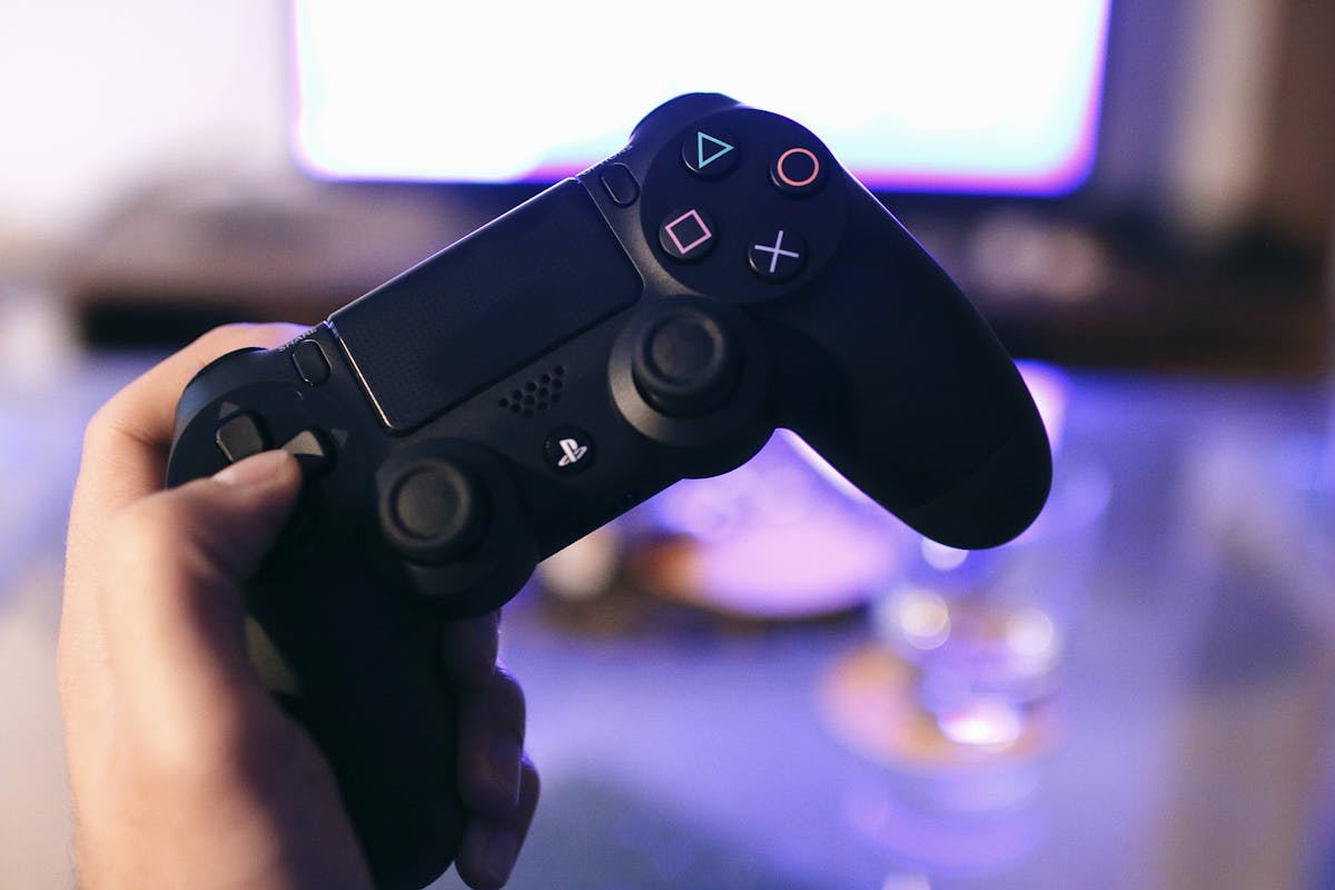 Person holding PlayStation gaming controller